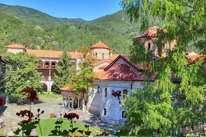 A historic church with red-tiled roofs, surrounded by lush greenery and hills. 2
