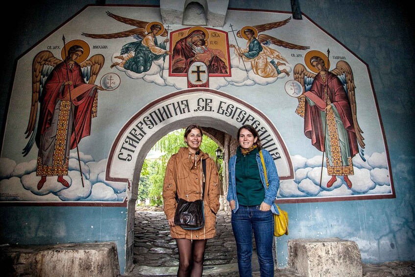 A religious mural with angels and crosses, and a stone archway with inscriptions. 4