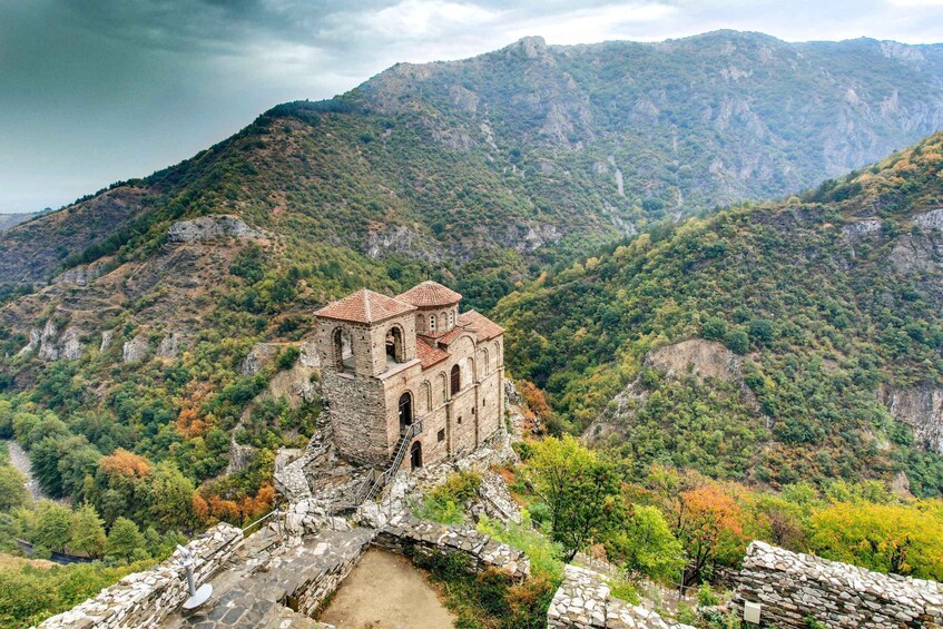 A historic stone church with a bell tower on a mountain. 1