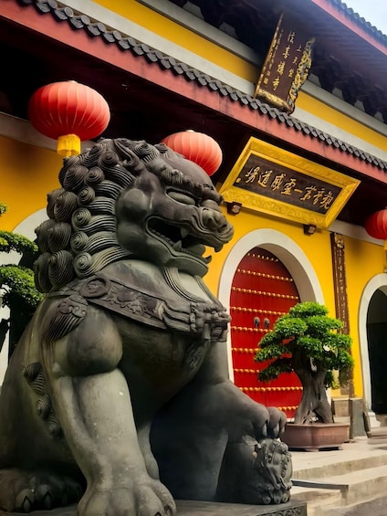 A lion statue in front of a traditional building with a red door and yellow walls. 4