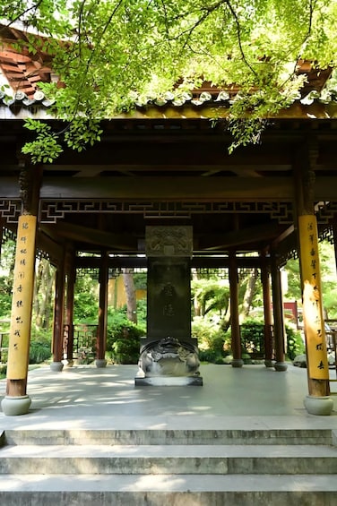 A traditional pavilion with a stone base, surrounded by lush greenery and a clear sky. 3