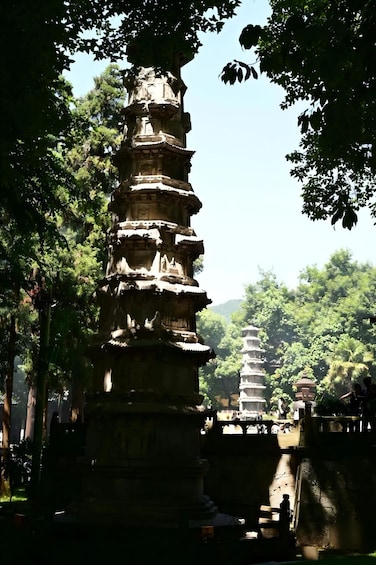 A pagoda-style tower with multiple tiers, surrounded by lush greenery and other similar structures in the background. 5
