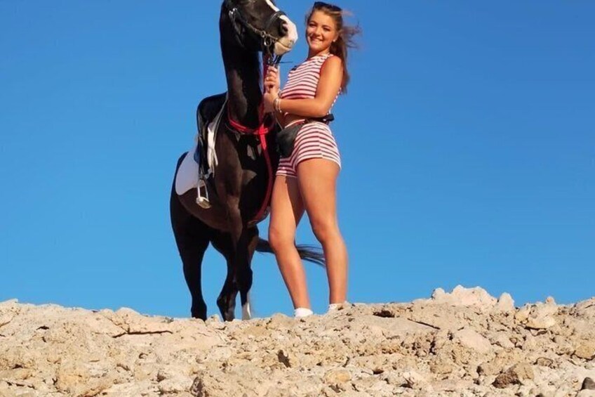 A person standing on a rocky terrain with a horse. 1