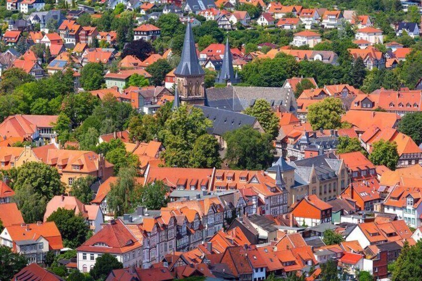 A densely packed town with red-roofed buildings and a prominent church spire. 1