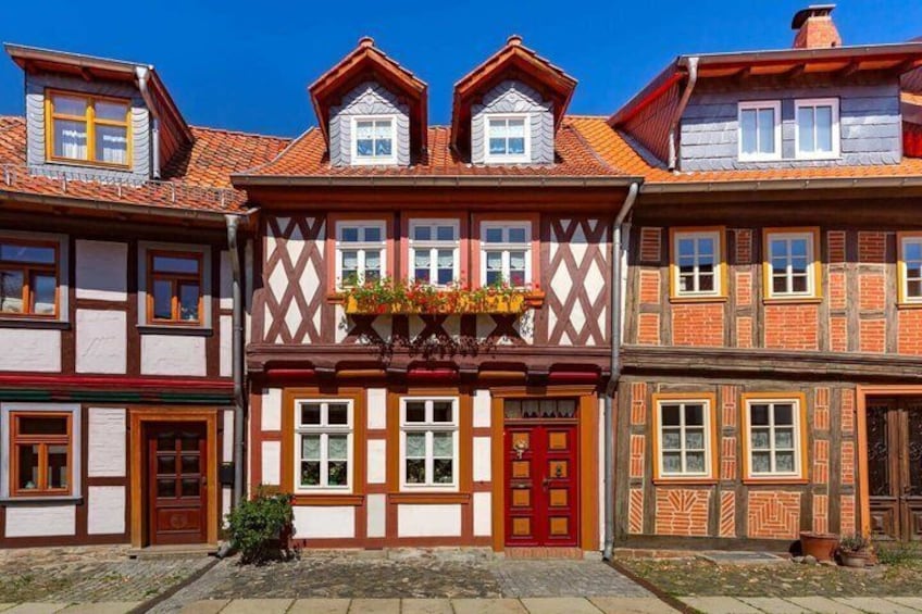 A traditional half-timbered building with a red door and a balcony with flowers. 5