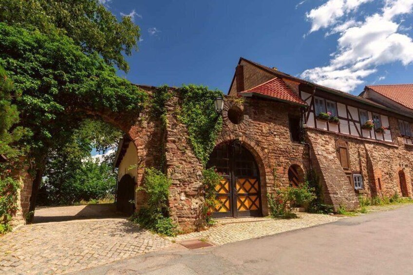 A historic stone building with a red-tiled roof, arched doorways, and a cobblestone path. 3