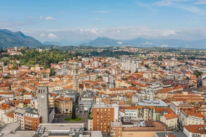 A panoramic view of a city with a prominent tower, dense urban buildings, and mountains in the background. 2