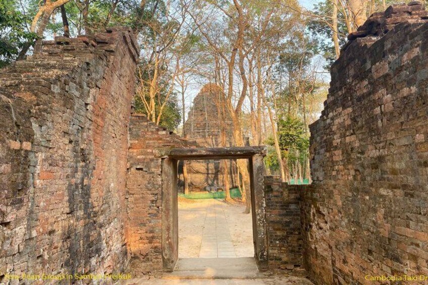An ancient brick structure with a covered entrance, surrounded by trees. 5