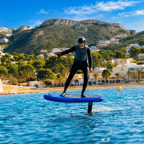 Une personne se tient debout sur une planche de paddle bleu, sur une étendue d’eau, avec un paysage montagneux en arrière-plan. 3