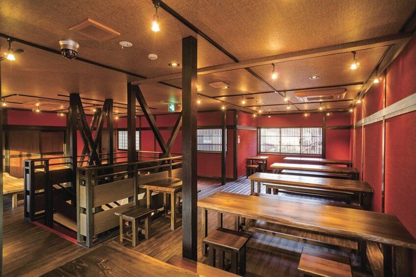 A restaurant interior with wooden tables and benches, red walls, and a staircase. 4