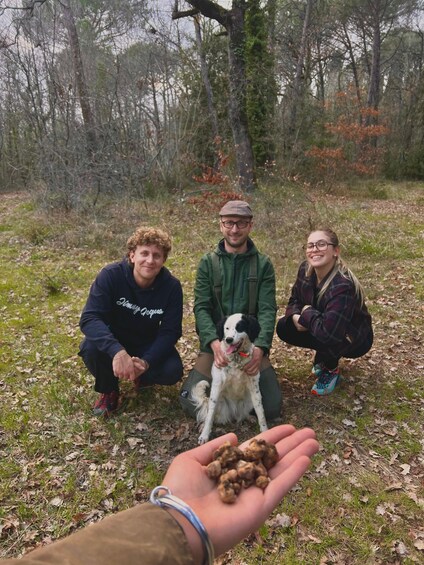 Three people in a forest with a dog and a hand offering nuts. 2