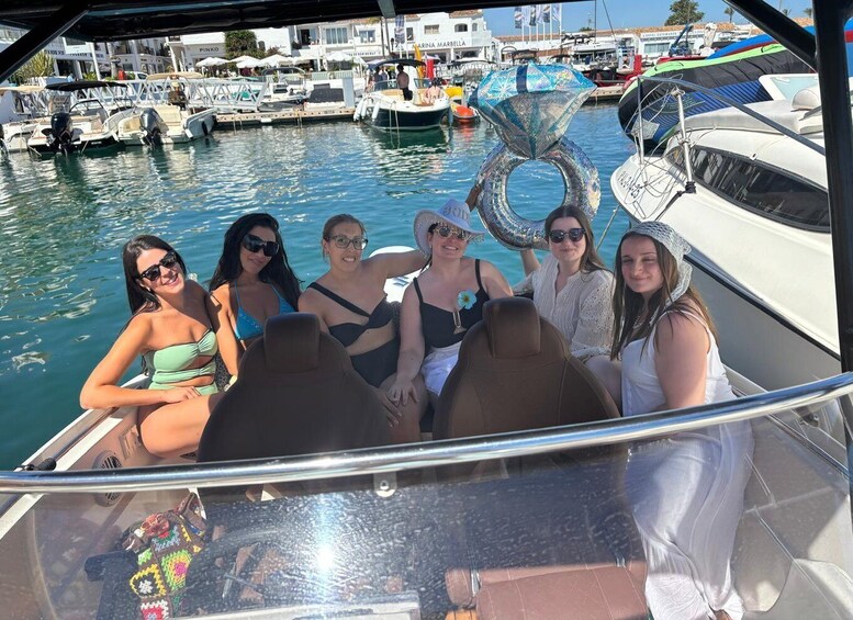 A group of people on a boat in a marina with other boats and buildings in the background. 4