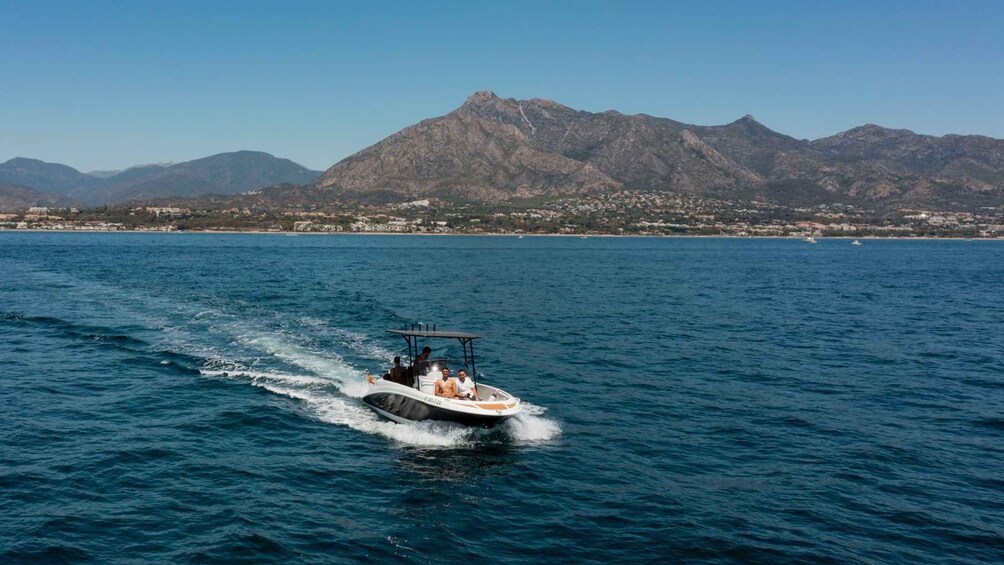 A speedboat on a calm sea with a mountainous coastline in the background. 2