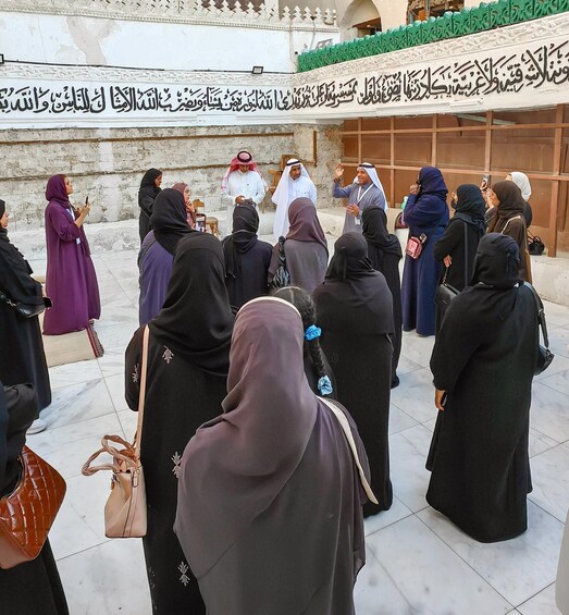A group of people gathered in front of a building with Arabic calligraphy. 5