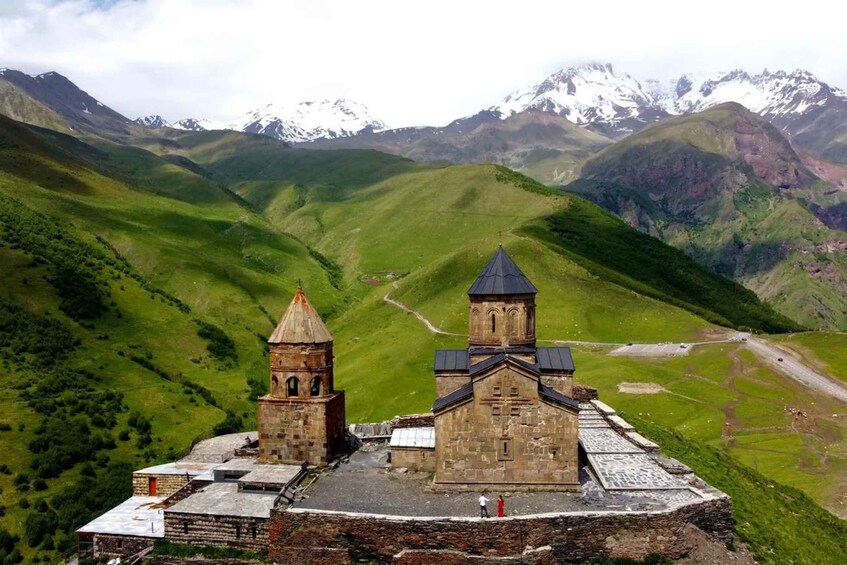 A church with two towers on a hillside with snow-capped mountains in the background. 3