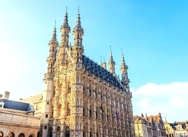 A historic building with intricate Gothic architecture, multiple spires, and flags. 1