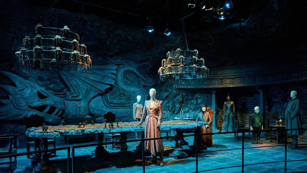 A museum exhibit with mannequins, a large dragon mural, and ornate chandeliers. 5
