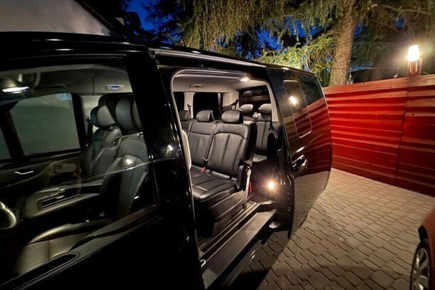 A black SUV with its rear door open, revealing a spacious interior with leather seats and a sunroof. 5