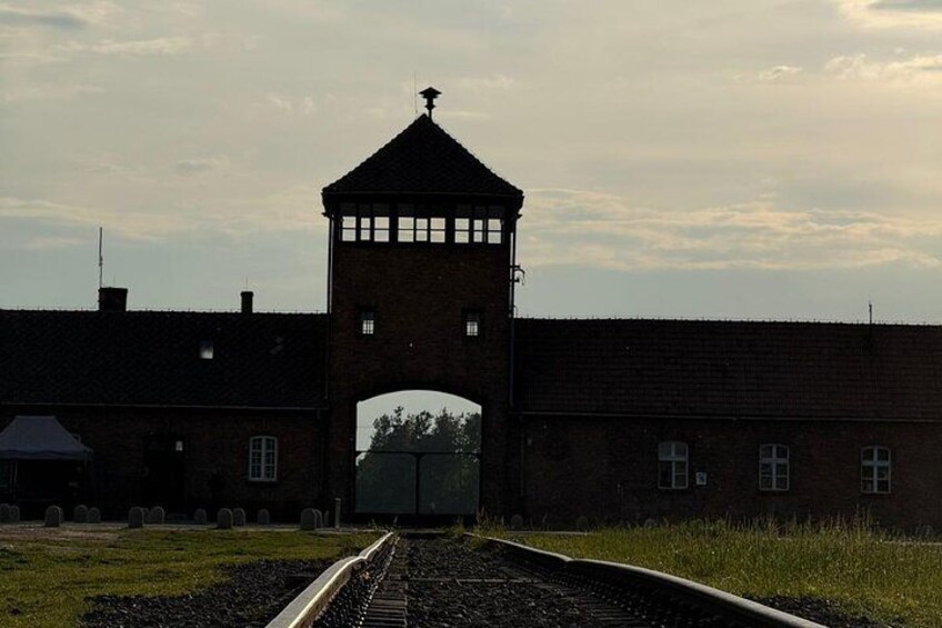 A railway track leading to a brick building with a tower. 3