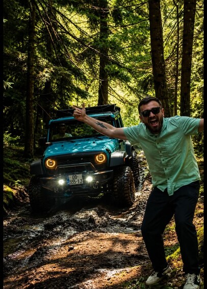 A person in a forest with a blue off-road vehicle. 1