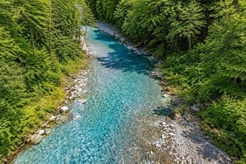 A clear river winding through a dense forest. 5
