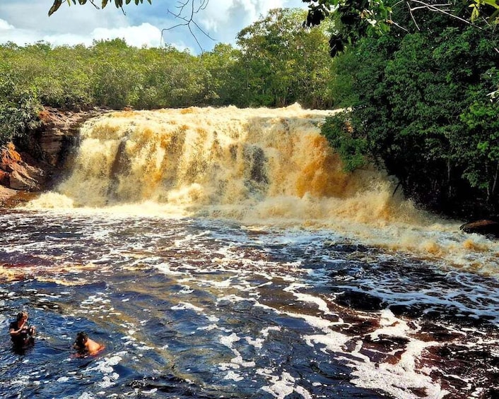 A waterfall cascading over rocks, surrounded by lush greenery. 2
