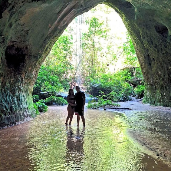 A couple standing in a cave with a waterfall in the background. 3
