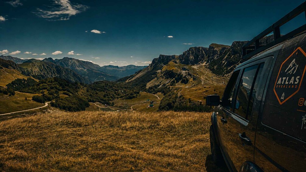 A mountainous landscape with a vehicle labeled 'Atlas Overland' parked on a grassy hill. 1