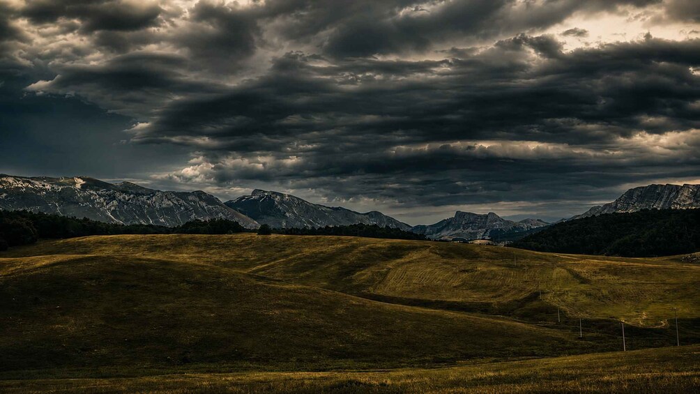 A mountainous landscape with rolling hills and a cloudy sky. 3
