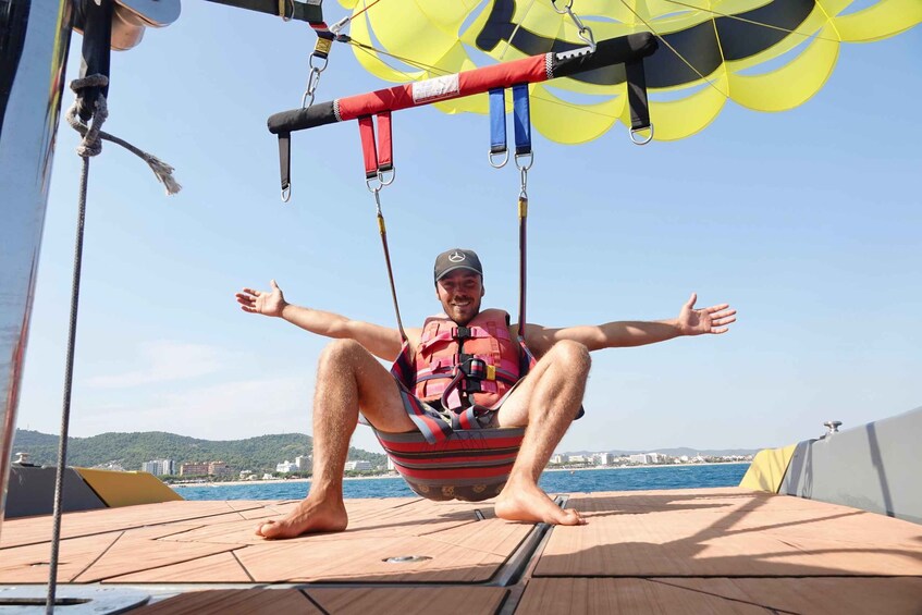 A person seated in a hammock on a boat, with a parasail in the background. 2