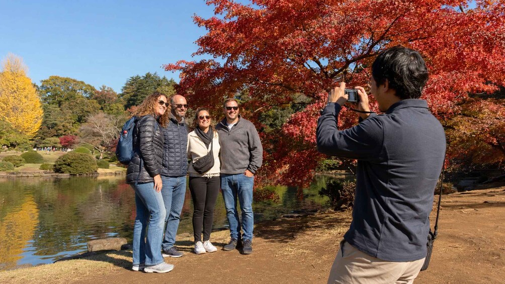 A group of people standing by a lake with autumn foliage. 5