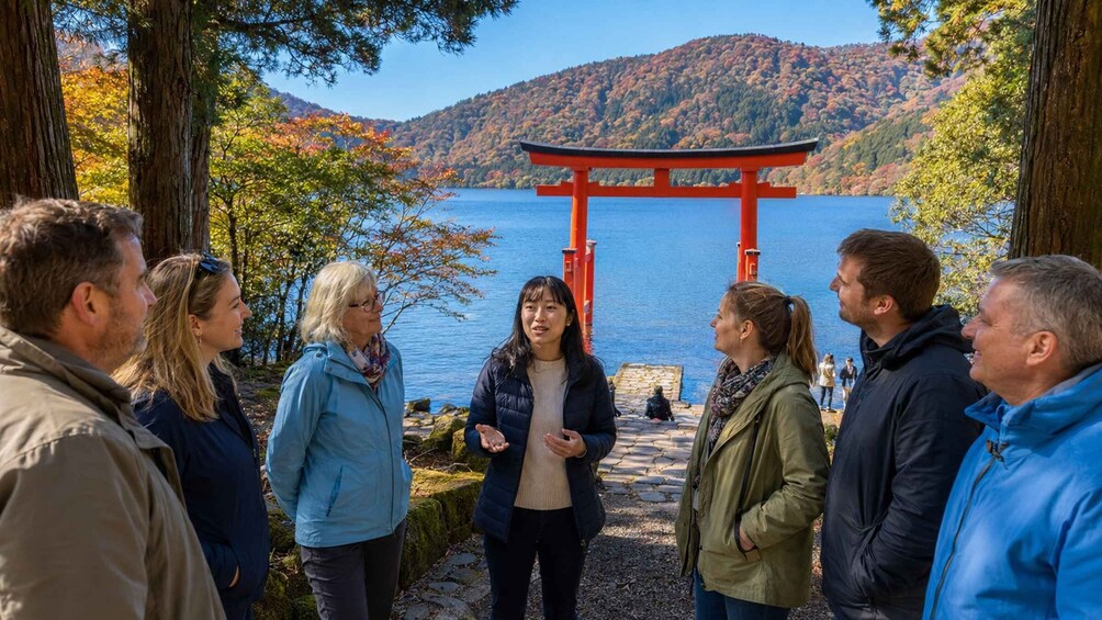 A group of people standing in a park with a red torii gate in the background. 4