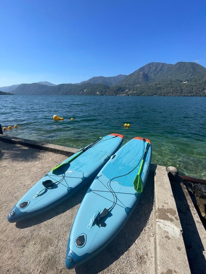 Two kayaks on a dock with a lake and mountains in the background. 3