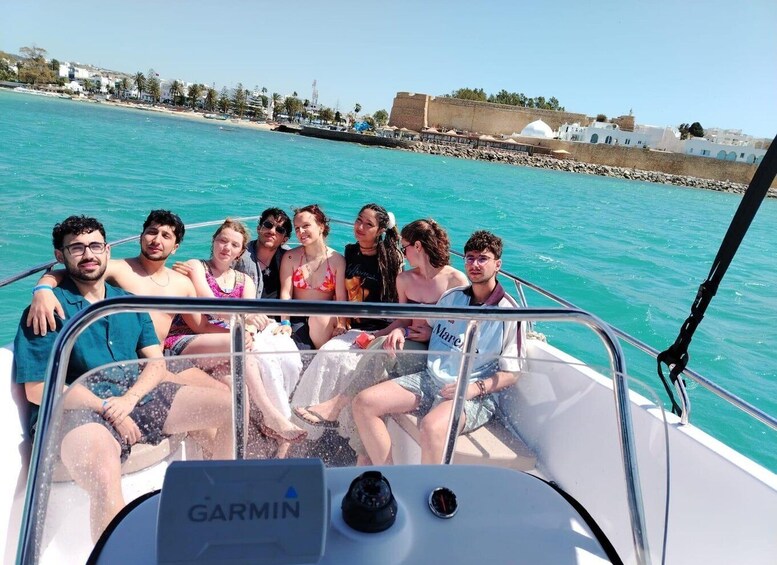 A group of people on a boat with turquoise water and a coastal town in the background. 5