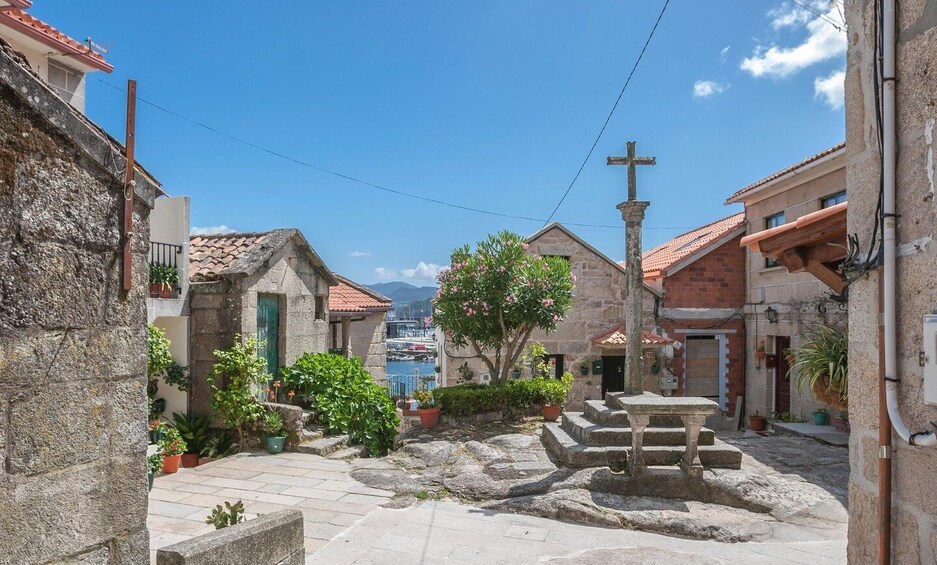 A stone courtyard with a fountain, potted plants, and traditional buildings with red-tiled roofs. 3