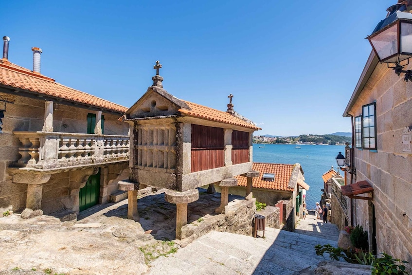 A coastal town with stone buildings, a clear blue sky, and a view of the sea. 1