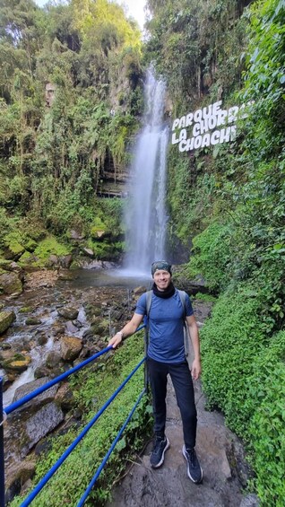 A person standing on a rocky ledge with a waterfall in the background. 3