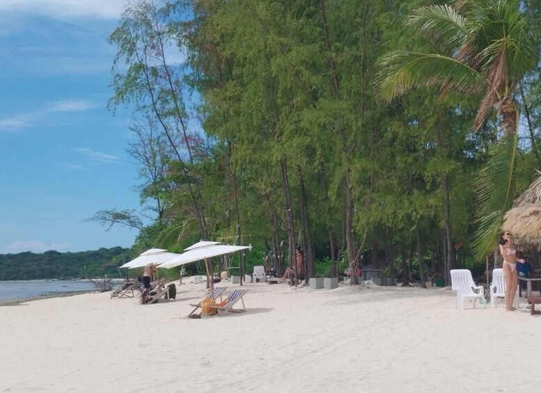 Ein Strand mit weißen Sonnenschirmen, Liegestühlen und Palmen. 5
