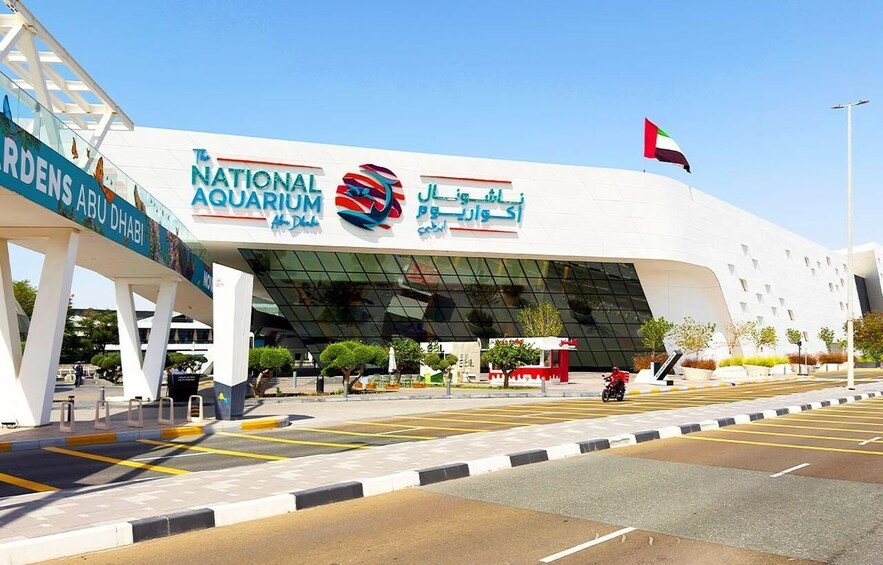 The National Aquarium building with a flag on top and a sign for Gardens Abu Dhabi. 5