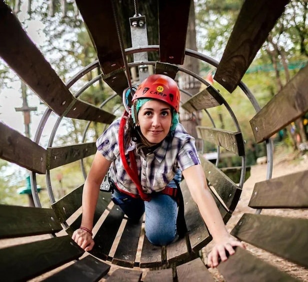 A person in a red helmet and plaid shirt crouching on a wooden spiral slide. 4