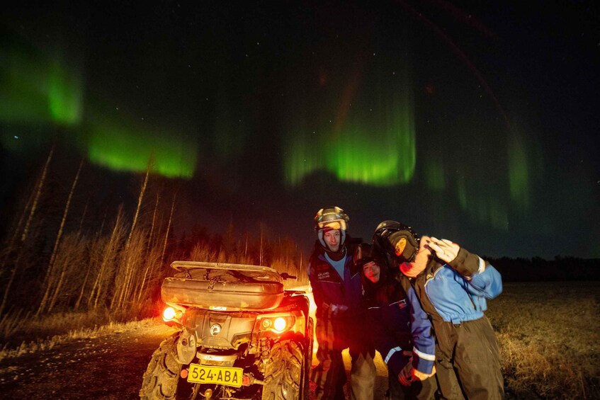 A vehicle with a license plate, people in outdoor gear, and the Northern Lights in the background. 4