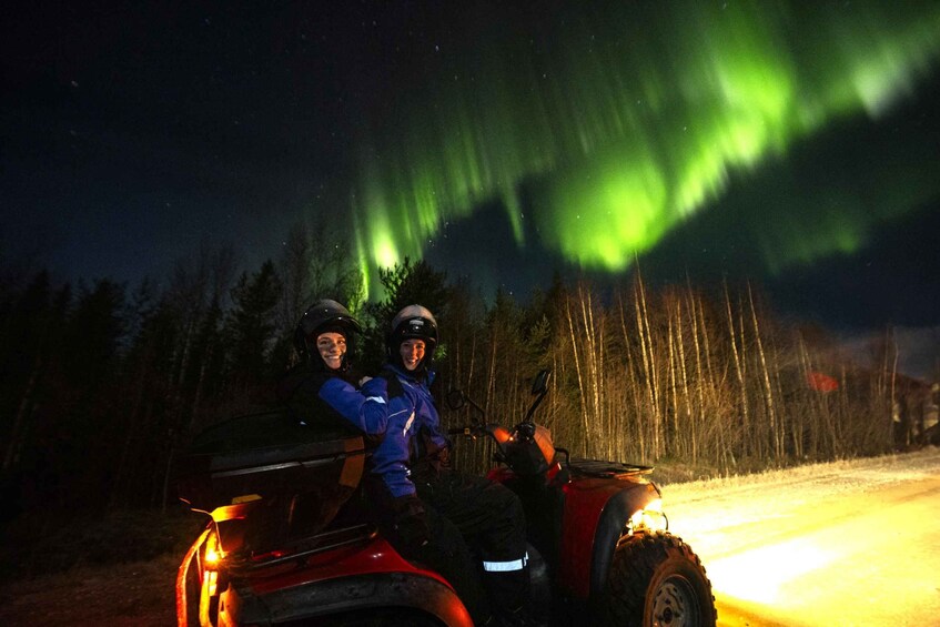 Two people in a red ATV under a night sky with green aurora borealis. 5