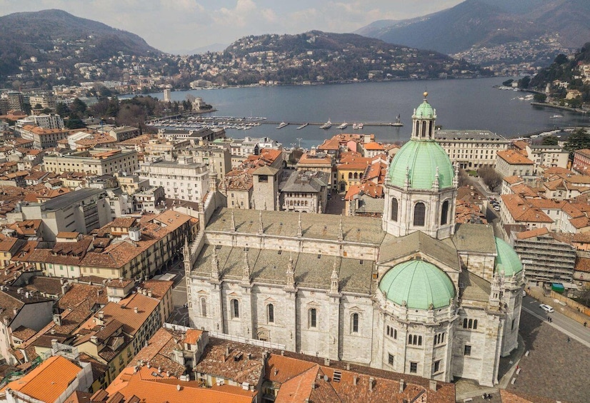 A cityscape with a prominent cathedral with a green dome, surrounded by historic buildings and a body of water in the background. 3