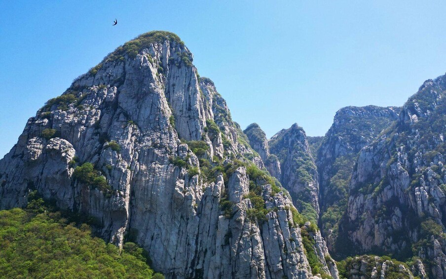 A rugged mountain landscape with steep cliffs and sparse vegetation. 2