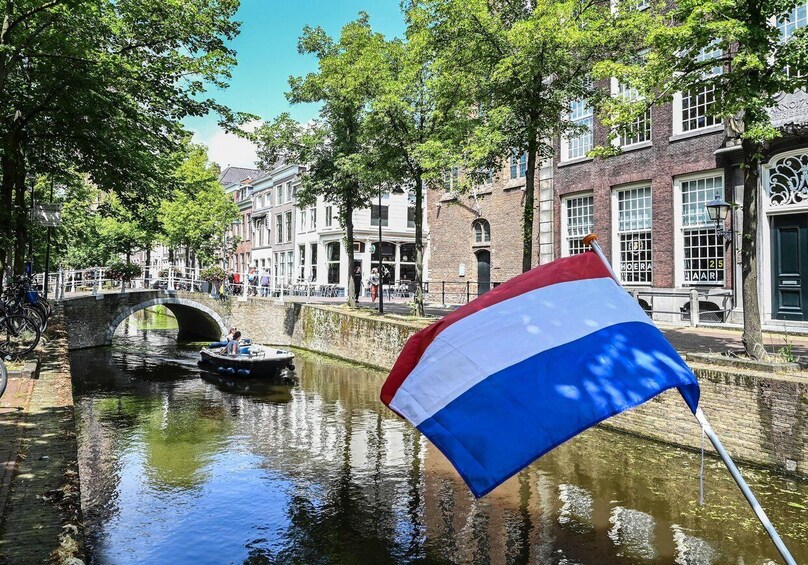 A canal with a boat, a bridge, and buildings with flags. 5