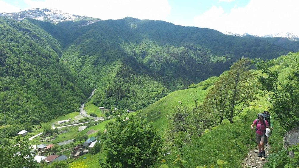 A hiker on a trail with a valley and houses in the background. 3