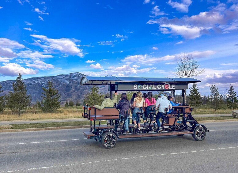 A group of people on a social cycle vehicle with a mountainous landscape in the background. 2