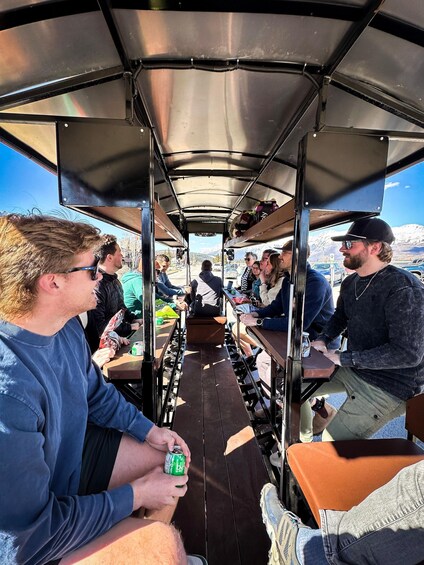 A group of people seated inside a covered bus, with a mountainous landscape visible through the windows. 3