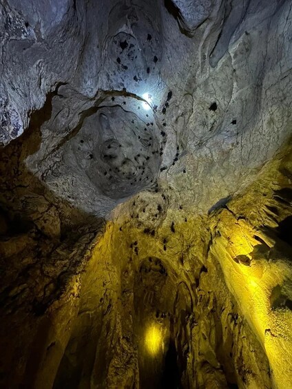 A cave with stalactites and stalagmites, illuminated by artificial lighting. 5