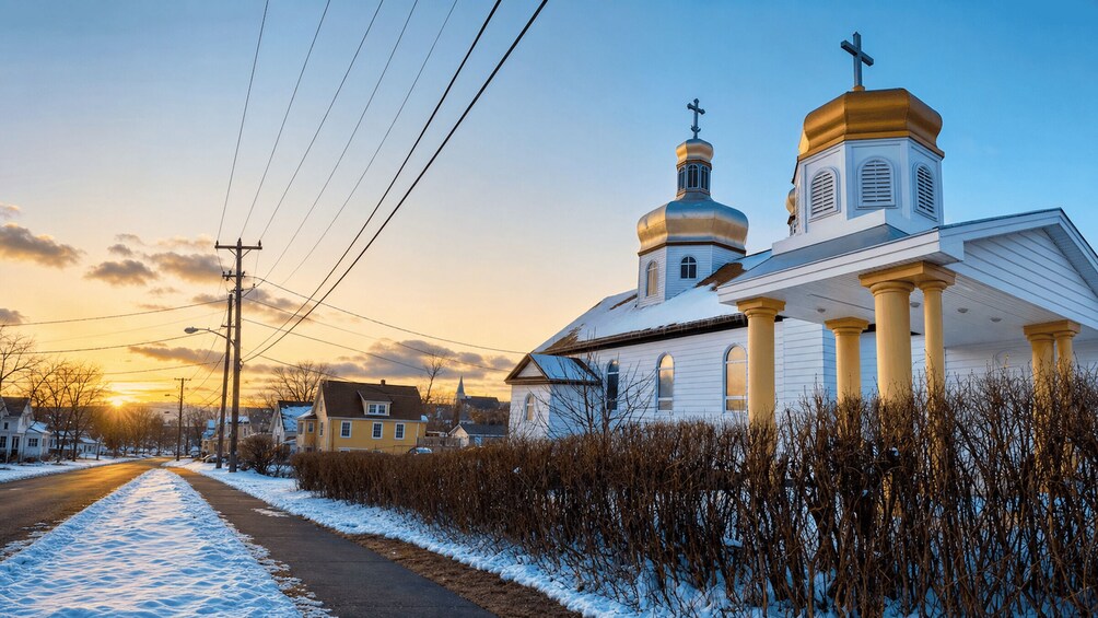 A church with two domes and a cross on top, surrounded by snow-covered ground and houses. 3